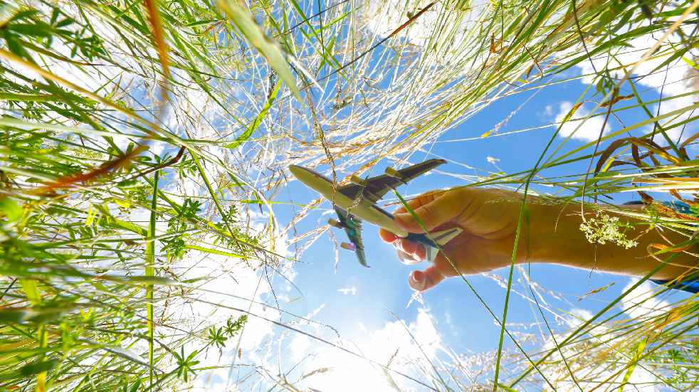 boy holding toy plane in grass